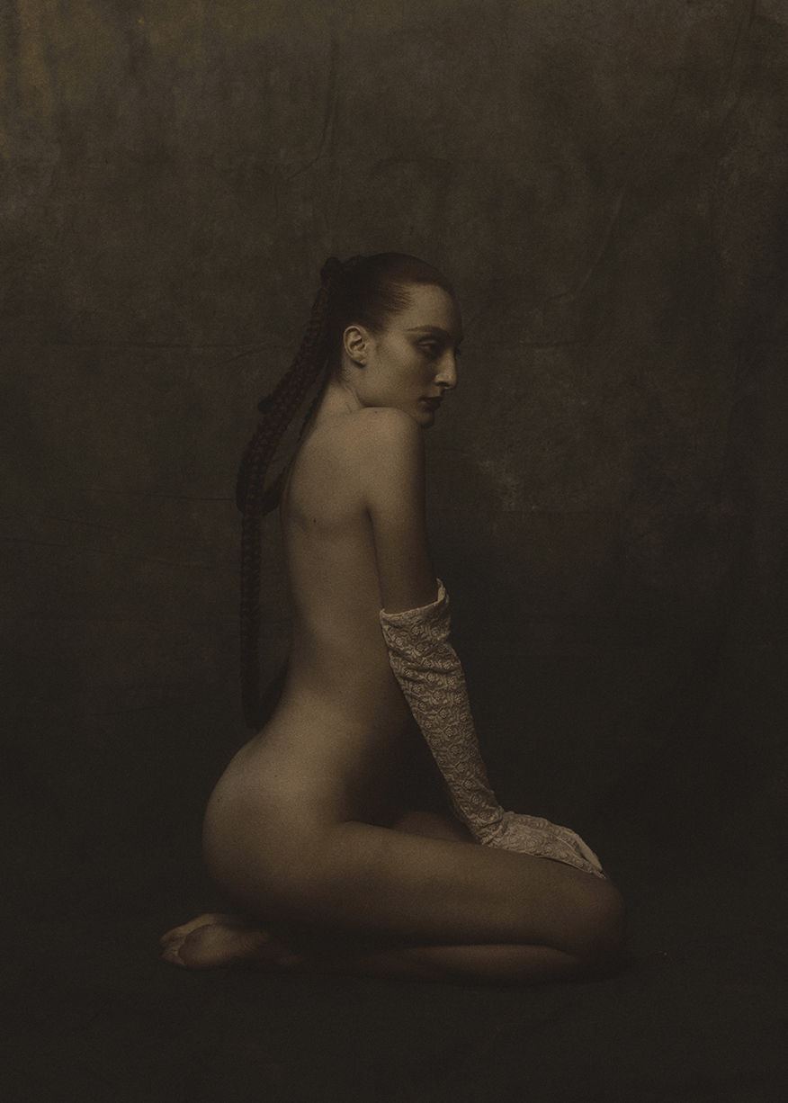 Seated figure in profile with a long braid and lace gloves