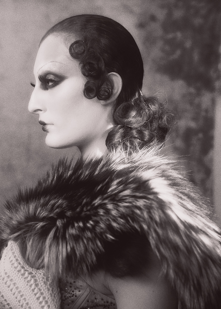 Black-and-white profile portrait with sculpted waves and a textured collar